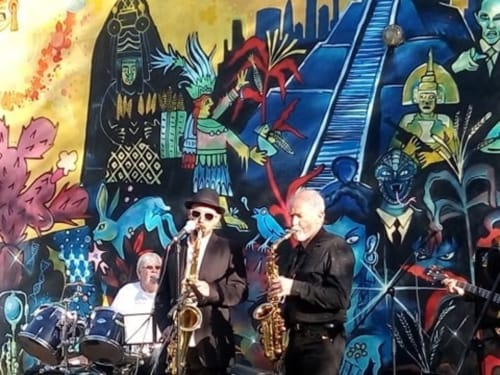Jazz musicians perform against vibrant murals at Le Lama Zébré, a unique BnB in Penmarch, France