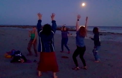 Group celebrating at dusk on Penmarch beach under moonlight at Le Lama Zébré guesthouse