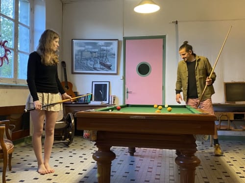 Two guests playing pool at Le Lama Zébré, a quirky B&B in Penmarch, France with artistic decor.