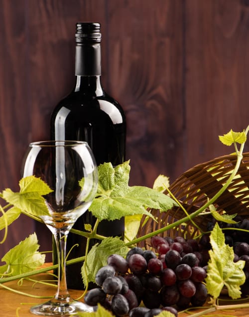 Bouteille de vin rouge et verre avec raisins noirs et feuilles de vigne au restaurant La Route d'Argent, Bozouls