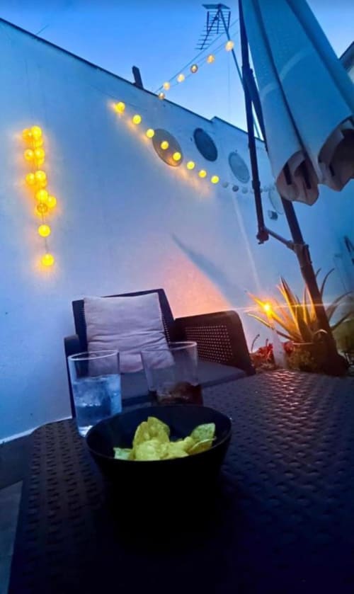 Terraza en la azotea al atardecer con aperitivos, bebidas y luces navideñas amarillas con vistas al paisaje urbano de Mérida