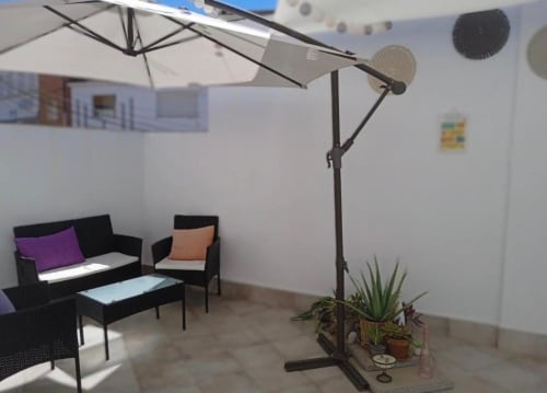 Área de estar en terraza exterior del apartamento Gestyp-AT en Mérida con sombrilla y plantas en macetas