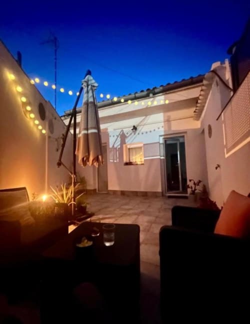 Terraza en la azotea nocturna con área de descanso, luces decorativas y vistas de la ciudad en Mérida