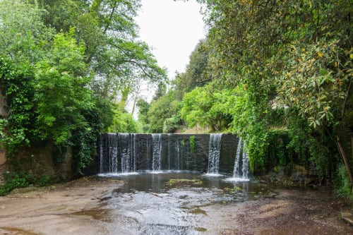 Suggestiva cascata che scende su una diga in pietra circondata da rigogliosa vegetazione verde vicino a Campagnano di Roma
