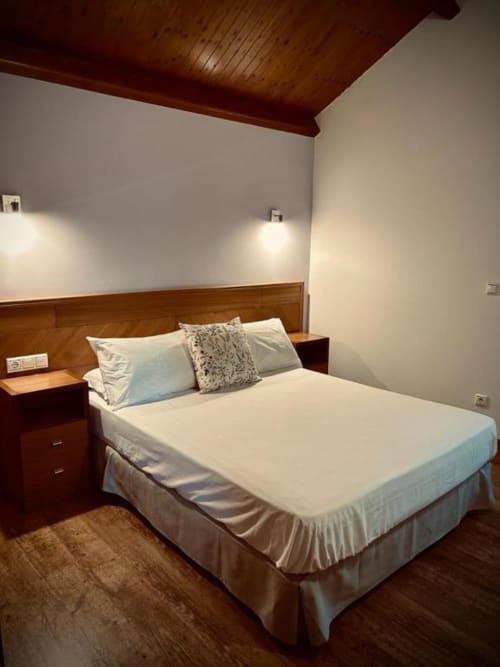 Habitación doble de lujo con cama de madera, ropa de cama blanca y vistas a las montañas en Casa Rural A Bouciña en Cangas, España