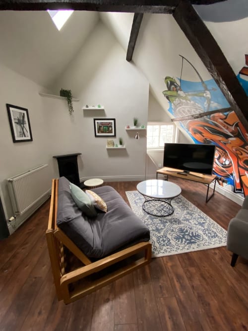 Modern apartment sitting area with wooden chair, TV, white coffee table, and colorful wall art in York city centre