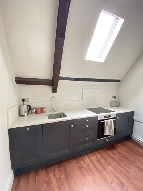 Modern kitchen in York apartment with dark cabinets, white counters, skylight, and stainless steel appliances