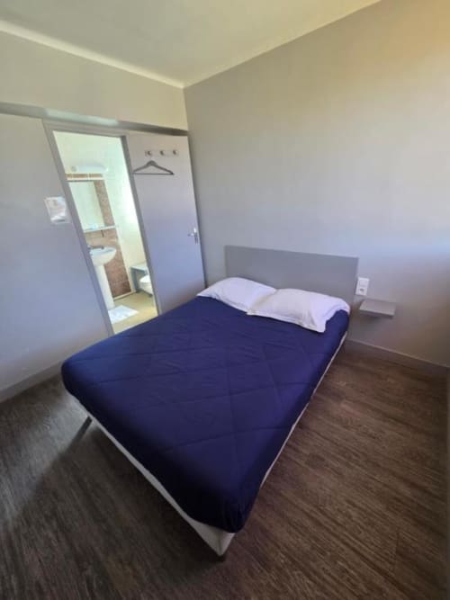 Chambre double moderne à l'hôtel Le Bel Air à Decize avec literie bleu marine, salle de bains attenante et décoration minimaliste