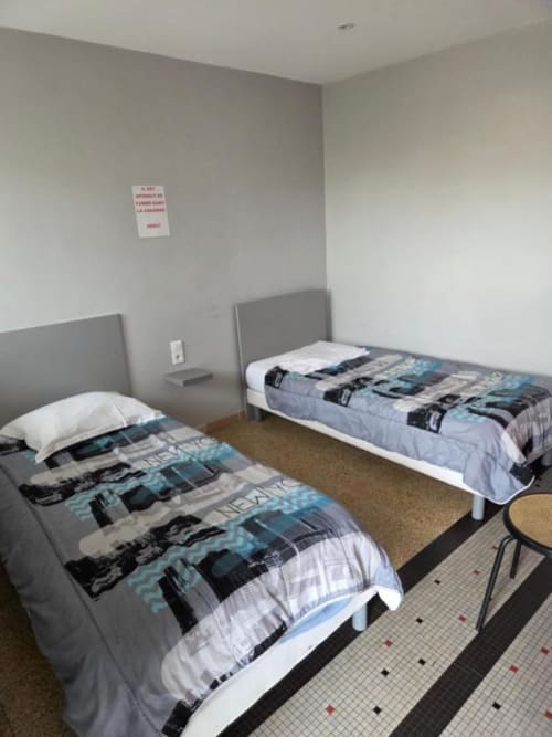 Chambre twin de l'hôtel Le Bel Air à Decize avec deux lits, têtes de lit grises et carrelage