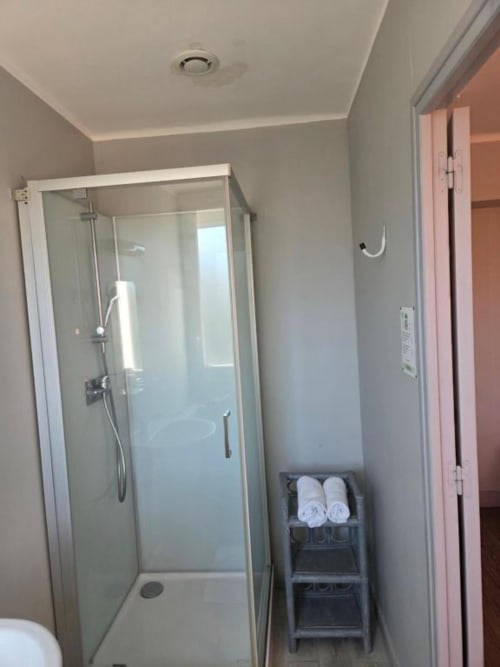 Salle de bain moderne avec douche vitrée, sanitaires blancs et porte-serviettes à l'hôtel Le Bel Air à Decize, France
