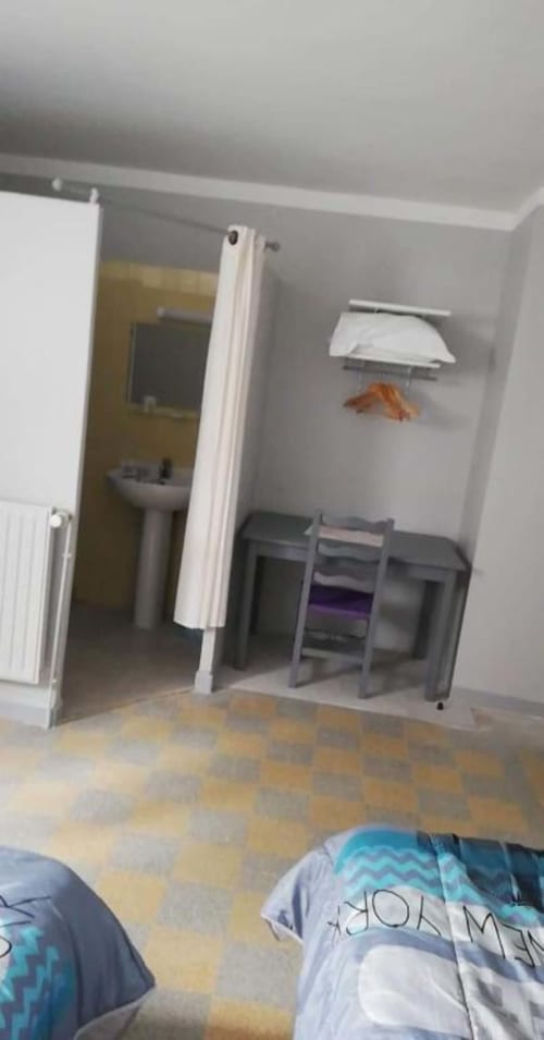 Spacieuse chambre triple de l'hôtel Le Bel Air à Decize avec sol carrelé, bureau et entrée de salle de bain