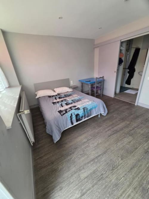 Chambre triple de l'hôtel Le Bel Air à Decize avec lit, bureau et vue sur la ville depuis la chambre mansardée