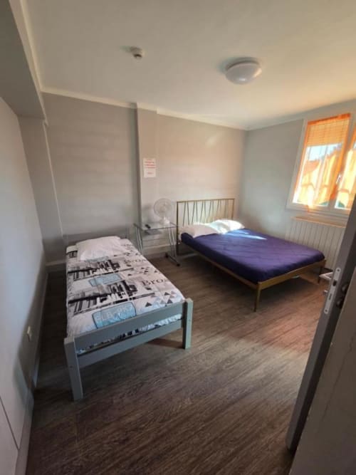 Chambre triple de l'hôtel Le Bel Air à Decize avec deux lits, parquet et vue sur la ville