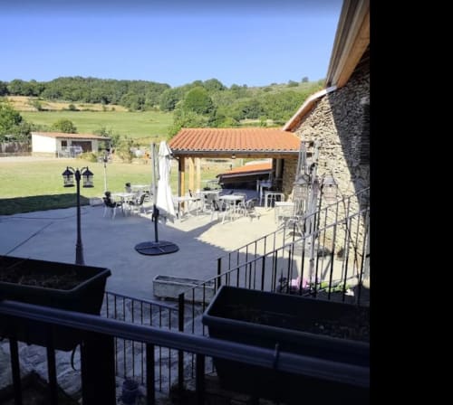 Patio de O Trancallo con edificios de piedra, terrazas y vistas a la campiña verde de Ourense