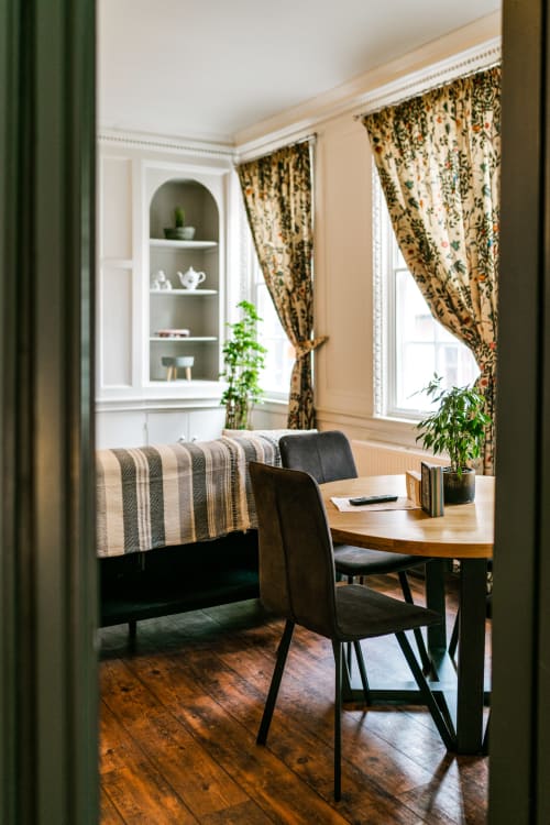 Elegant apartment workspace at Stonegate Townhouse York with wooden desk, black chair, striped bench, large windows,