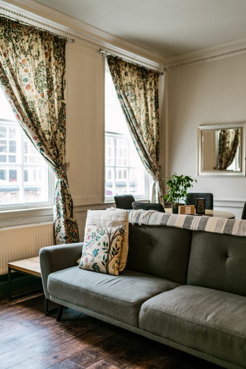 Elegant living room in Stonegate Townhouse York apartment with gray sofa, floral curtains, and city views