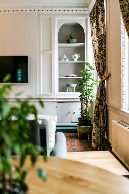 Elegant living room in Stonegate Townhouse York apartment with white built-in shelving, potted plants, decorative tea