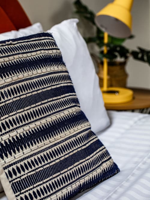 Navy and cream striped pillow on bed at Stonegate Townhouse York apartment with yellow lamp and plants