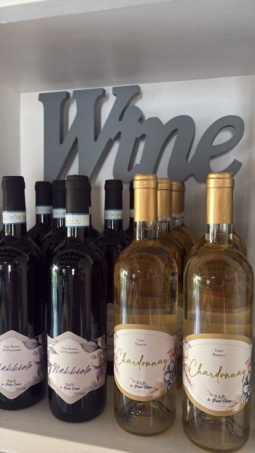 Bottiglie di vino esposte alla Dolce Casa B&B di Cremia, Italia - vini Nebbiolo rosso e Chardonnay bianco con insegna 'Wine'