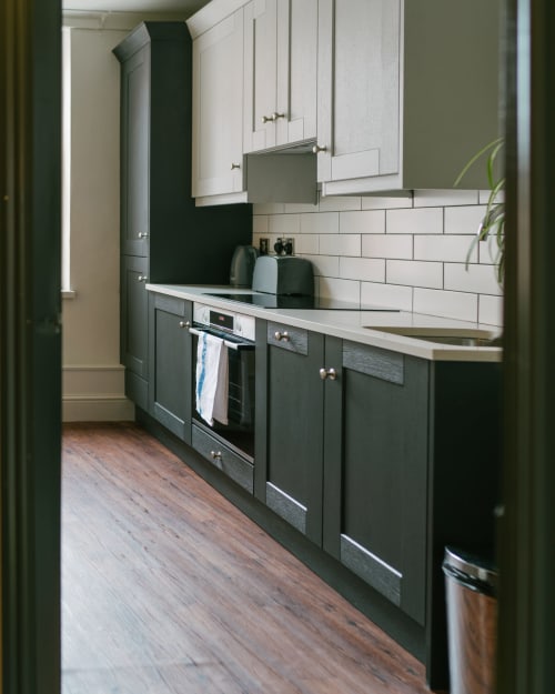 Modern kitchen in Stonegate Apartment, York, with dark lower cabinets, white upper cabinets, subway tile backsplash, and
