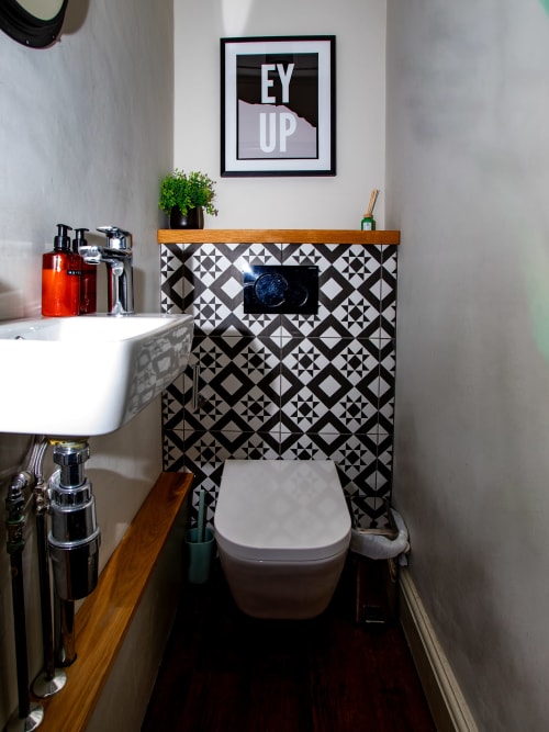Modern bathroom in Stonegate Townhouse York apartment with geometric black and white tile walls, white toilet, wooden vanity,