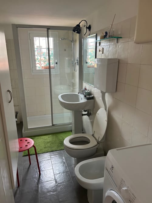Bagno moderno nell'appartamento di Bologna con doccia, WC, lavabo a colonna e finestre con vista sulla città