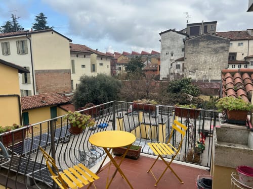 Terrazza soleggiata con arredi gialli che affaccia sui storici edifici di Bologna e i tetti in cotto
