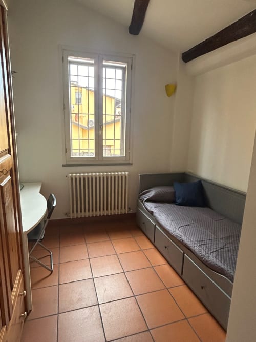 Accogliente camera con letto singolo, scrivania e finestra con vista su Bologna nel loft L'Appartamento Giusto