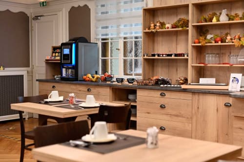 Cuisine et salle à manger modernes de l'Hôtel de l'Ange avec mobilier bois, tables de restaurant et cafetière