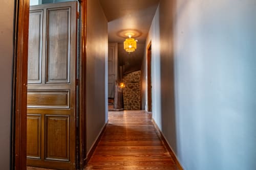Élégant couloir de la Bise de la Jouvence B&B à Saint Laurent sur Sèvre avec portes en bois, éclairage chaleureux et parquet