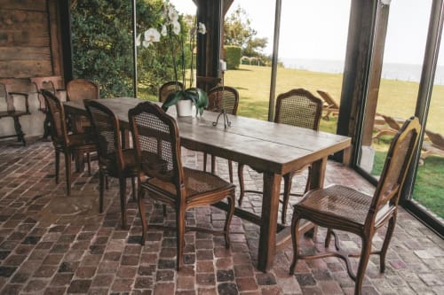 Élégante salle à manger de la Chambre d'hôtes La Girelle à Honfleur avec table en bois, chaises en rotin et vue sur le jardin