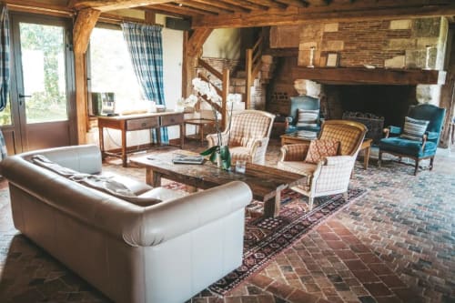Salon rustique à la villa La Girelle à Honfleur avec poutres apparentes, cheminée, coin détente et vue sur mer par les fenêtres