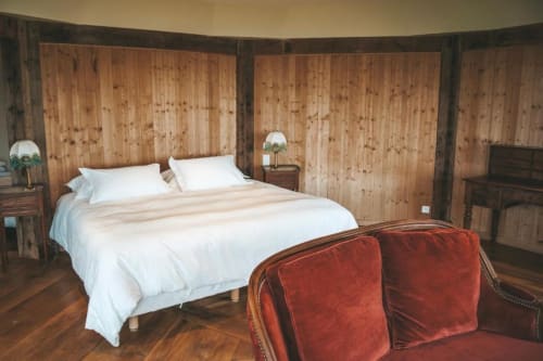Spacieuse chambre à La Girelle avec murs en pin noué, literie blanche, fauteuils en velours rouge et mobilier en bois à Honfleur