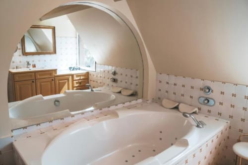 Salle de bains luxueuse à La Girelle Honfleur avec baignoires balnéo doubles, meuble vasque en bois et carrelage crème