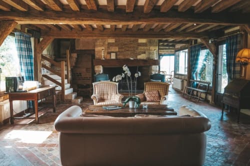 Salon rustique aux poutres apparentes de la Girelle B&B à Honfleur avec canapé en cuir marron, fauteuils écossais et briques exposées