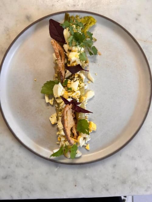 Plat élégamment dressé au restaurant La Route d'Argent à Bozouls : viande rôtie, légumes et herbes fraîches