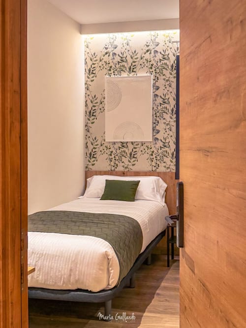 Habitación individual del Hotel Síbel Baza con dos camas, papel pintado botánico, ropa de cama blanca y detalles verdes