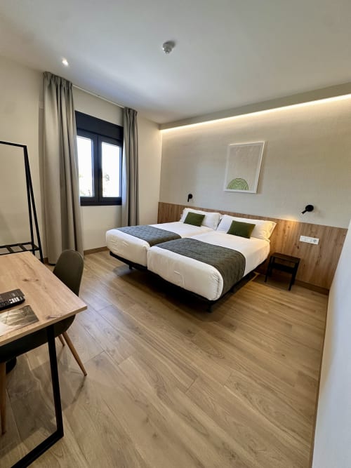 Moderna habitación doble en Hotel Síbel Baza con dos camas, cabecero de madera, escritorio y vistas a la montaña