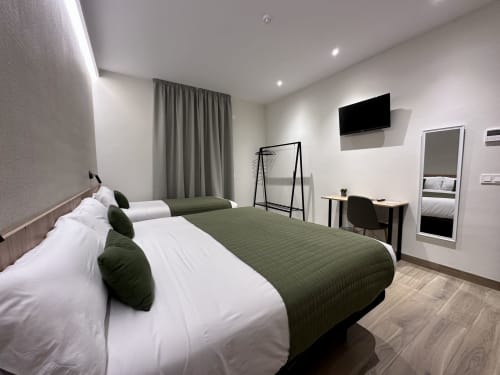 Habitación moderna del hotel Síbel Baza con cama matrimonial, detalles en verde, televisor de pantalla plana y escritorio de trabajo