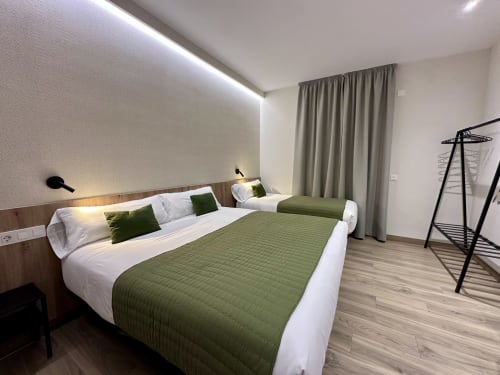 Moderno dormitorio triple en el Hotel Síbel Baza con camas individuales, ropa de cama verde y comodidades contemporáneas