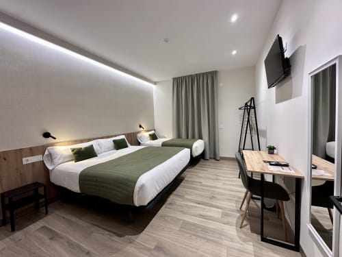 Moderna habitación triple del Hotel Síbel Baza con cama queen, escritorio de trabajo, TV y vistas a las montañas en Baza