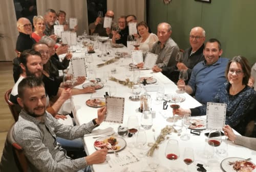 Des clients savourant un repas gastronomique à La Route d'Argent à Bozouls, assis à une longue table blanche avec du vin