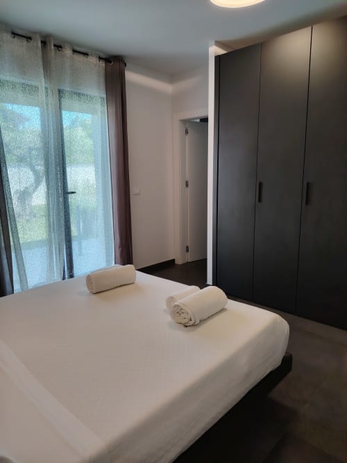 Deluxe double room at Green Land Boutique Hotel with white bed, rolled towels, garden view windows, and black wardrobe in
