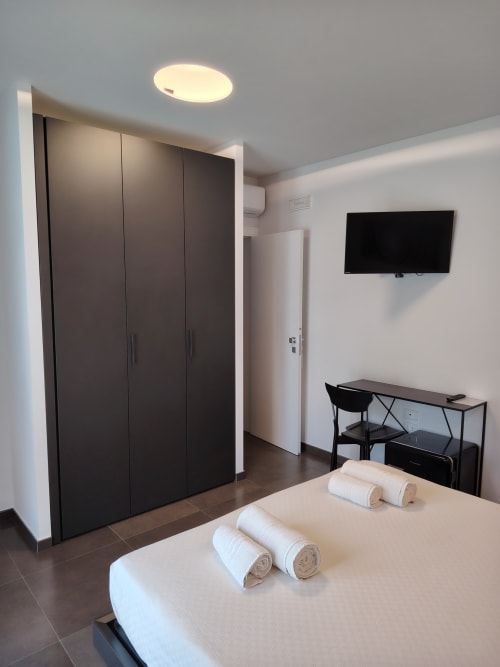Modern Deluxe Double Room at Green Land Boutique Hotel with bed, black wardrobe, desk, wall-mounted TV, and garden view in