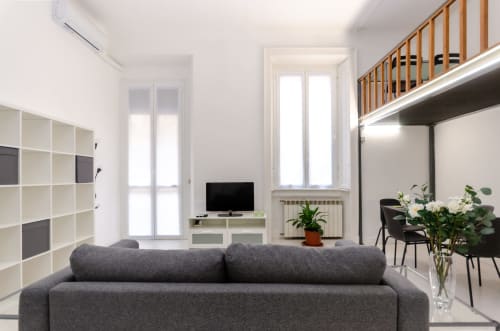 Soggiorno moderno a Milano con divano grigio, TV, librerie e loft in soppalco presso Bronzetti Home