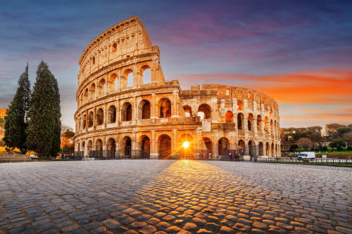 Antico Colosseo romano al tramonto a Roma, Italia con luce dorata e cipressi