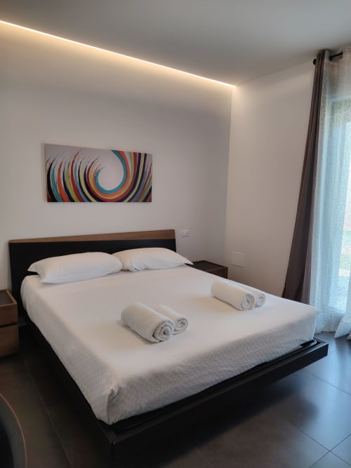 Camera moderna al Green Land Boutique Hotel di Castilenti con letto platform, biancheria bianca, arte murale colorata e illuminazione ambient