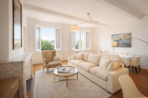 Bright living room with cream sofa, fireplace, and garden views at Suite Roi René, Les Suites de Montigny, Aix-en-Provence
