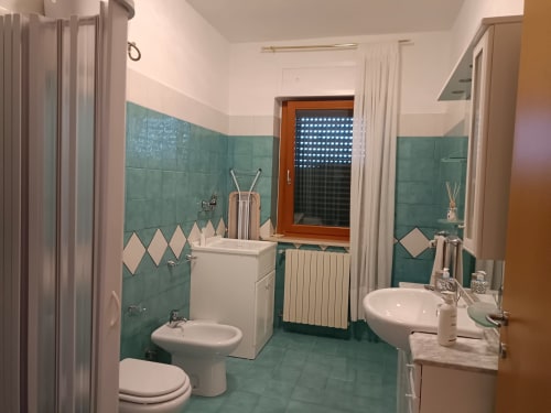 Bagno della Bike Green House con piastrelle color teal, doppio lavabo, bidet e toilette presso Tales of Abruzzo, Atessa