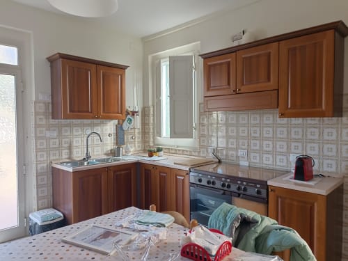Cucina con mobili in legno, rivestimento in piastrelle beige, fornello e piani di lavoro nell'appartamento Bike Green House